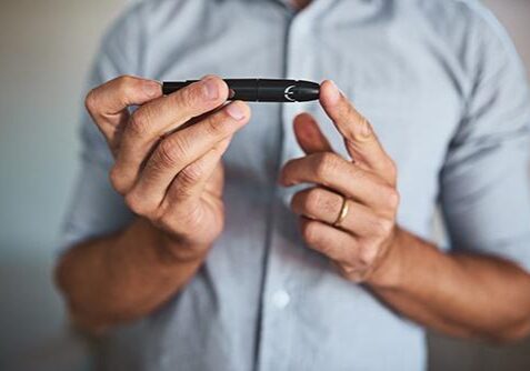 Shot of an unrecognizable man holding an insulin injection pen with his hands at home during the day